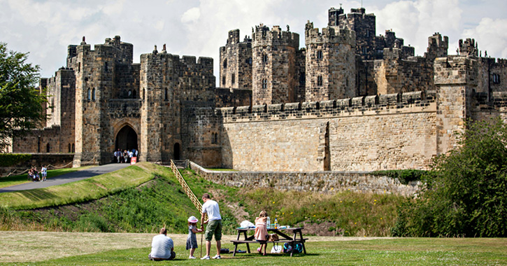 family eating picnic with Alnwick Castle clear in the background